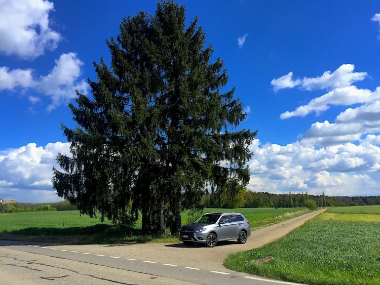 Mitsubishi Outlander PHEV auf Landstrasse vor Baum