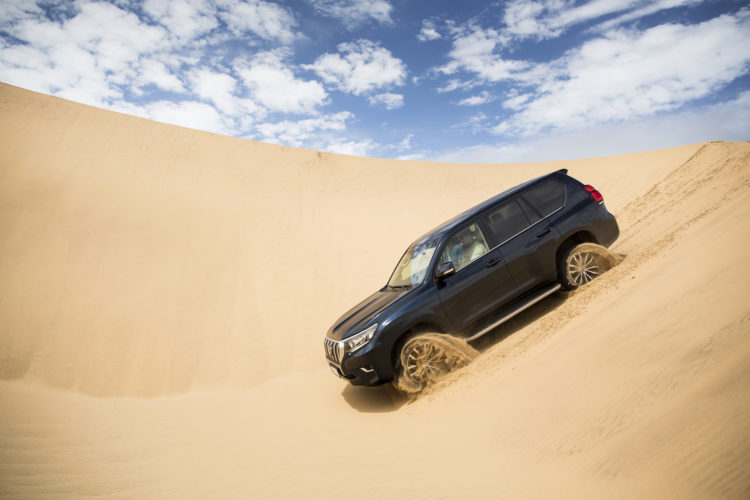 Toyota Land Cruiser gleitet über eine Sand-Dühne